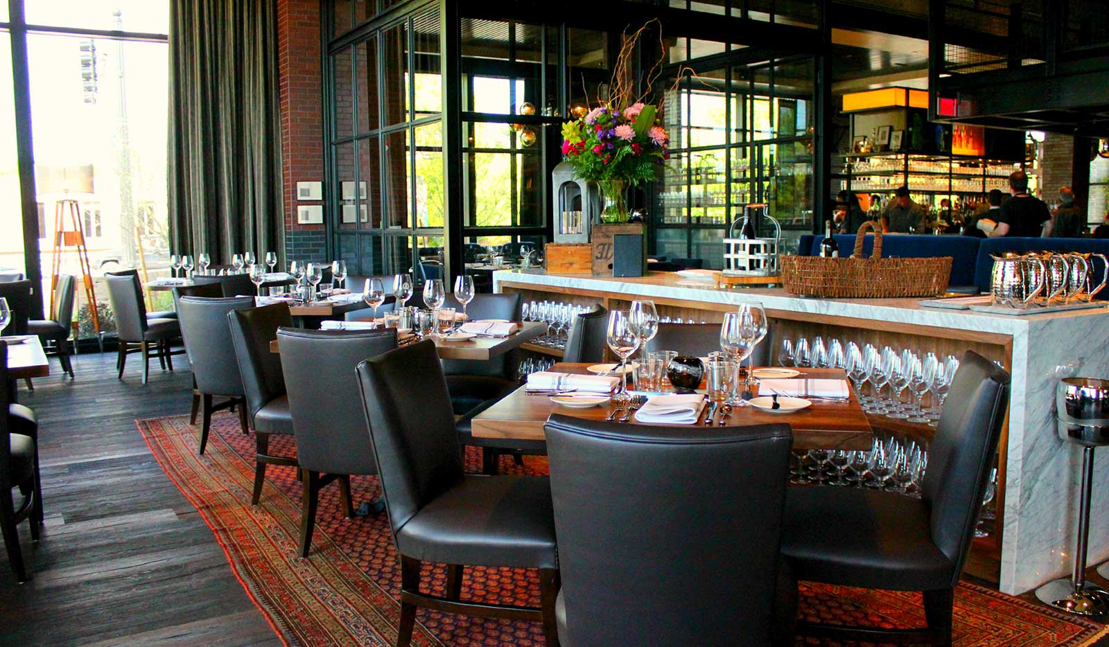 View of dining room with marble service stations, leather chairs and steel and glass enclose room. 